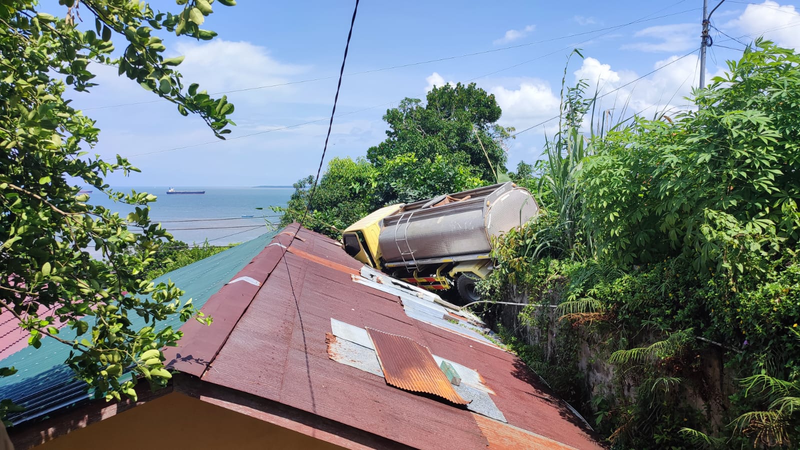 Waduh! Truk Tangki Air Hinggap di Atap Rumah Warga